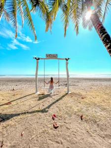 Una donna seduta su un'altalena su una spiaggia di Alma del Pacifico Hotel & Spa a Esterillos Este