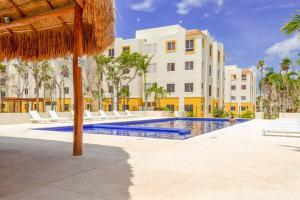 a resort swimming pool with white lounge chairs and an umbrella at Cozy Tulum Oasis: 2-Bedroom w/ Pool in Tulum