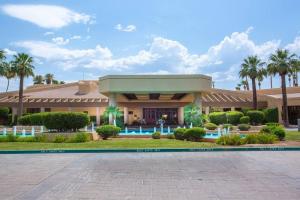 a resort building with a swimming pool and palm trees at Sunny Palm Desert Escape on Golf Course in Palm Desert