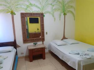 a room with two beds and a mirror and two palm trees at Pousada Porto Seguro in Porto De Galinhas