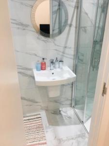 La salle de bains blanche est pourvue d'un lavabo et d'une douche. dans l'établissement MIA Residence - Entire Studio apartment - City View - London - Next to Ealing Broadway Station, à Ealing