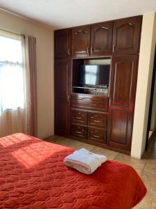 a bedroom with a bed and a cabinet with a tv at Apartamento #3 Portal de Occidente in Quetzaltenango