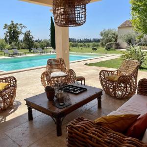 um pátio com uma mesa e cadeiras e uma piscina em Le Mas Saint Philippe em Jonquières