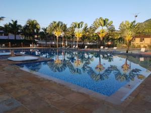 Una gran piscina con palmeras al fondo. en Maresias Beach Housing - Mata Azul, en São Sebastião