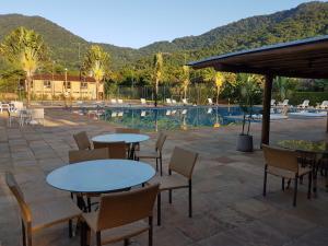 un patio con tavoli e sedie accanto alla piscina di Maresias Beach Housing - Mata Azul a São Sebastião