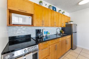 une cuisine avec des armoires en bois et des appareils en acier inoxydable dans l'établissement Ocean View, Steps to Waikiki Beach and Free Parking, à Honolulu