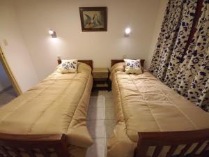 2 Betten in einem kleinen Zimmer mit Vorhängen in der Unterkunft LA SAN JUAN en Zona Norte in San Miguel de Tucumán