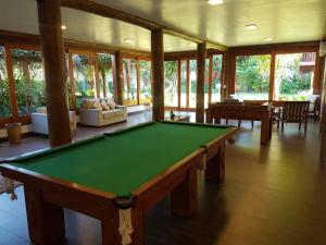 una mesa de billar en una sala de estar con ventanas en Maresias Beach Housing - Mata Azul, en São Sebastião
