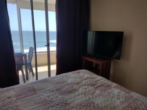 1 dormitorio con cama, TV y balcón en La Serena Sol y Mar, en La Serena