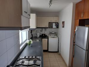 a small kitchen with a stove and a refrigerator at La Serena Sol y Mar in La Serena