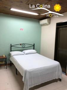 uma cama num quarto com uma placa de hotel na parede em Hotel la colina em Cartago