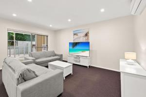 a living room with a couch and a tv at Pacific Blue 520 private pool air conditioning and Wi Fi in Salamander Bay