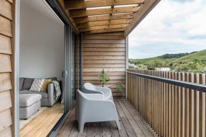 een terras met een bank en een stoel op een balkon bij Wainui Landing Apartment 1 in Raglan
