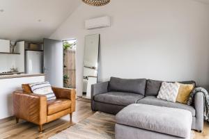 uma sala de estar com um sofá e uma cadeira em Wainui Landing Apartment 1 em Raglan