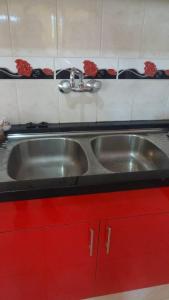 a kitchen with a stainless steel sink and red cabinets at Hostal El Paraiso in Tarija