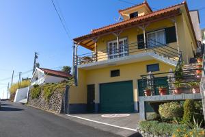 une maison jaune avec un garage vert dans l'établissement Typical Madeira Orchid House, à Calheta