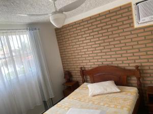 a bedroom with a bed and a brick wall at condomínio Porto di Mare Casa 22 ALAGOAS in Paripueira