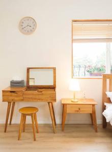 een bureau met een spiegel, een kruk en een klok bij Bandi House in Seogwipo
