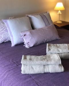 1 cama con 2 almohadas y toallas en Departamento Leloir Neuquén en Neuquén