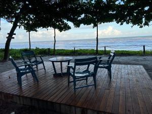 einen Tisch und Stühle auf einer Holzterrasse mit Strand in der Unterkunft Cumuru pé na areia in Cumuruxatiba