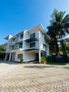 a white building with a palm tree in front of it at SATRA WAYANAD in Kalpetta