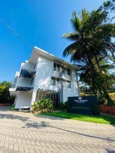 a white building with a palm tree in front of it at SATRA WAYANAD in Kalpetta