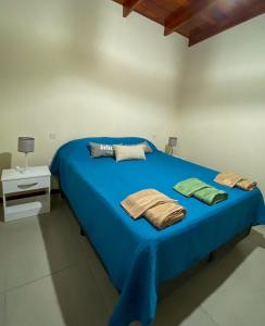 Una cama azul con toallas en una habitación en Pinares del Norte en Federación