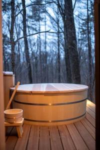 a bath tub sitting on a wooden deck with a window at Tatehata House. Private Sauna. Outdoor Bath. in Kita-karuizawa