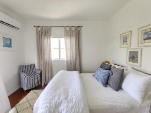 una camera con un letto bianco e una sedia di Eugarie Seaside Guesthouse a Marcoola