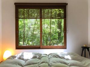 a window in a room with a bed in front of it at Tatehata House. Private Sauna. Outdoor Bath. in Kita-karuizawa