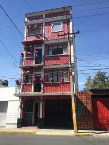 ein hohes rotweißes Gebäude mit Balkonen darauf in der Unterkunft Hotelito Ejido de la 10 in Puebla