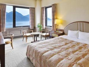 宮島にある宮島コーラルホテルの大きなベッドと大きな窓が備わるホテルルームです。
