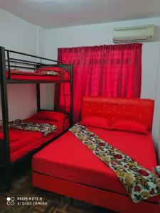a bedroom with two bunk beds with red sheets at PD Laguna Homestay Red in Port Dickson