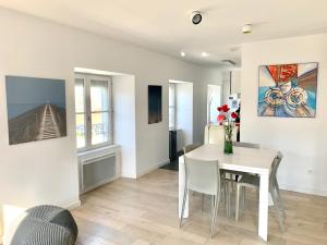 a white dining room with a white table and chairs at LE TI ROCHELAIS, superbe appart, design, cosy, vieux-port au calme in La Rochelle