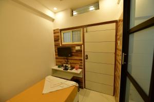 Cette petite chambre comprend un lit, un bureau et une télévision. dans l'établissement Hotel Surya Lodge, à Mysore