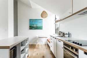 a kitchen with white cabinets and white counters at Wainui Landing Apartment 2 in Raglan