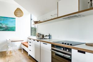 a kitchen with white cabinets and a counter top at Wainui Landing Apartment 2 in Raglan