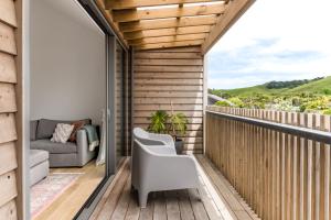 a balcony with a couch and a chair at Wainui Landing Apartment 2 in Raglan