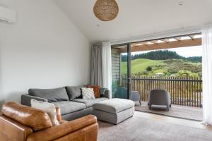 a living room with a couch and a balcony at Wainui Landing Apartment 2 in Raglan