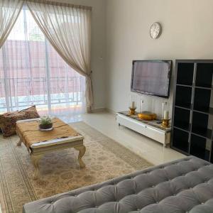 sala de estar con sofá, mesa y TV en Santai Homestay Jb, en Johor Bahru