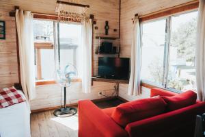 sala de estar con sofá rojo y 2 ventanas en Don Tito, en Aguas Dulces