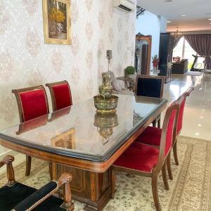 a dining table with a glass top and red chairs at Santai Homestay Jb in Johor Bahru