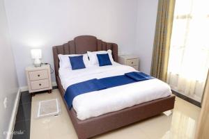 a bedroom with a large bed with blue and white sheets at Luxe Furnished Premium Unit in Meru