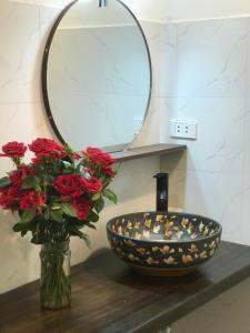 ハノイにあるMinh Vy House 16 Hàng Vôi Cozy Aparment, super fast internet, kitchen and washerの赤いバラの花瓶とバスルームの洗面台