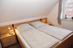 ein Bett in einem Schlafzimmer mit zwei Nachttischen und einem Fenster in der Unterkunft Wattvogel in Greetsiel