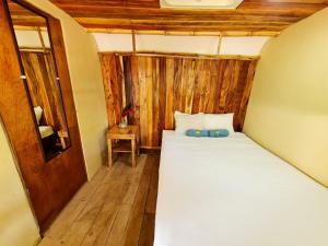 a bedroom with a bed in a room with wooden walls at Hospedaje Combi dream bird in Guanacaste