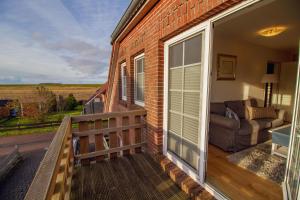 - un balcon d'une maison avec un canapé et une fenêtre dans l'établissement Greetsieler Inselhuus - Westwind, à Greetsiel
