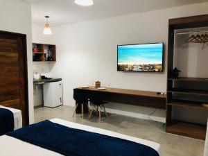 a bedroom with a desk and a tv on the wall at Marinho Suítes Milagres in São Miguel dos Milagres