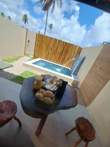 a table with a tray of food on it next to a pool at Marinho Suítes Milagres in São Miguel dos Milagres