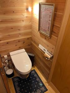 a bathroom with a toilet in a wooden room at Guesthouse Kazura in Nanto